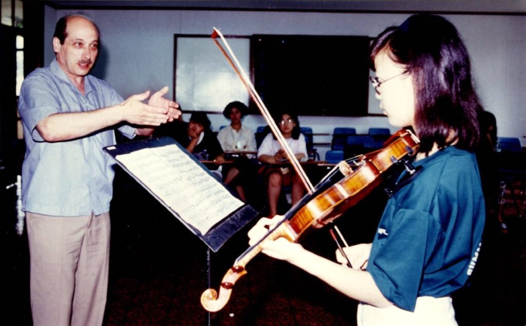 A woman playing the violin in front of other people.