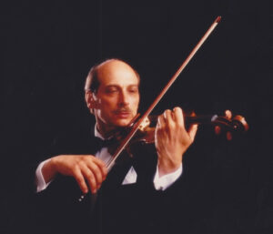 A man playing the violin in front of a black background.